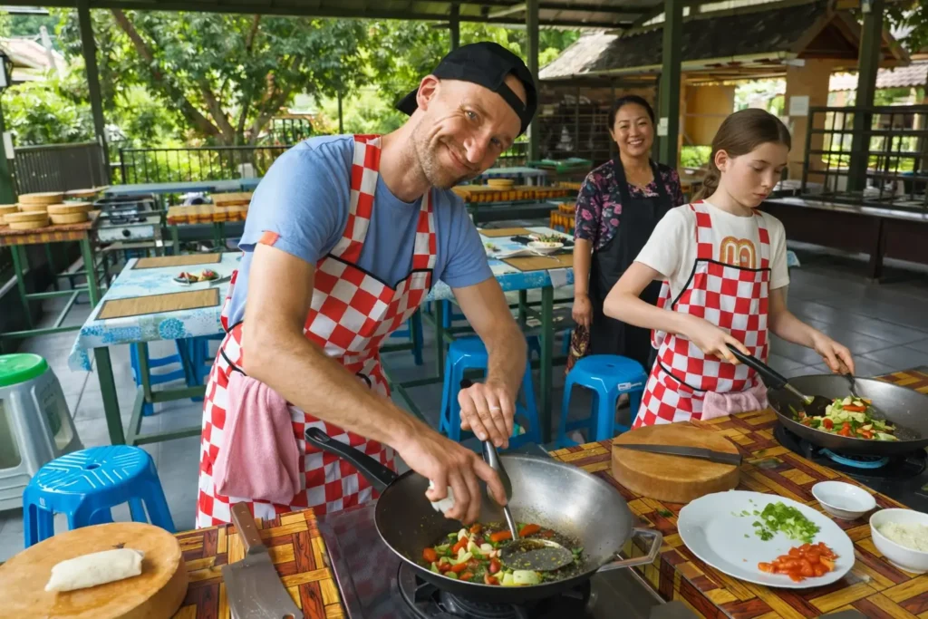 travelers taking part in a Thai cooking class, cooking vegetables in woks at an open-air kitchen surrounded by tropical greenery